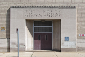 Südliche Berufsschule mit einer Tür und Schildern an der Wand, mit einem Wegweiser zur Eingangstreppe.