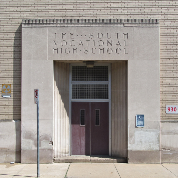 Südliche Berufsschule mit einer Tür und Schildern an der Wand, mit einem Wegweiser zur Eingangstreppe.