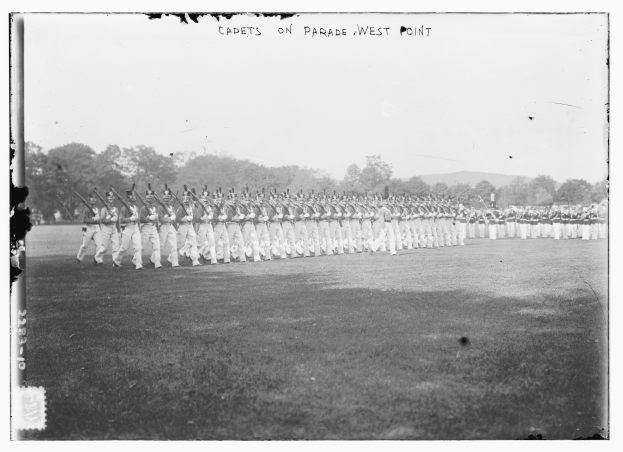Eine Gruppe von Menschen, einige mit Waffen in der Hand, die in Formation vor Bäumen, Hügeln und einem bewölkten Himmel stehen, mit dem Text "cadets on parade west point" oben.