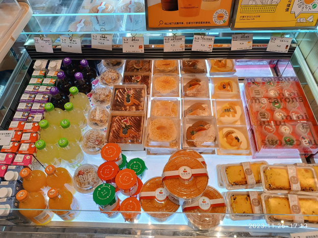 Ein Supermarktvitrinenregal mit verschiedenen Lebensmittelartikeln wie Flaschen und Schachteln mit Preisschildern an der Scheibe.