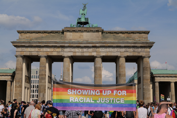 Eine Gruppe von Menschen steht vor dem Brandenburger Tor in Berlin, Deutschland, und hält ein Banner mit der Aufschrift "Rassengerechtigkeit."
