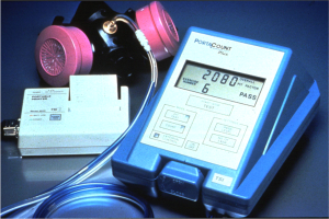 Eine Gasmaskierung wird auf einem Tisch neben einem elektronischen Gasdetektionsgerät mit einem angeschlossenen Kabel platziert.