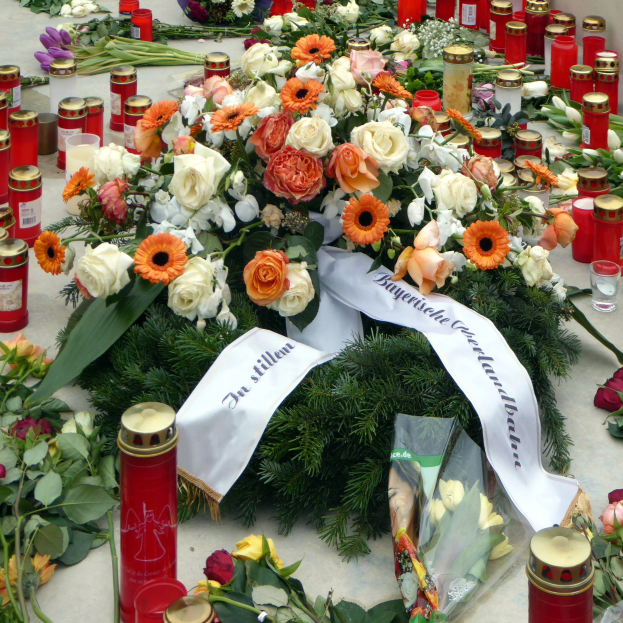 Mahnmal in Berlin, Deutschland, mit Blumen und Kerzen vor einer Wand auf dem Boden