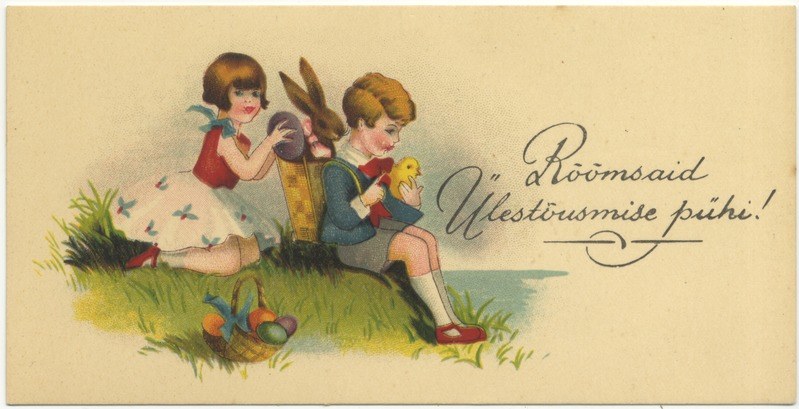 Alte Postkarte mit zwei Kindern auf dem Gras sitzend, eines hält einen Korb mit Ostereiern und das andere ein Spielzeug, im Hintergrund ein Plakat mit Text.