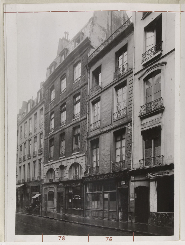 Schwarz-weiß-Foto einer Stra├če mit Geb├Ąuden mit Fenstern, Gel├Ąndern und Namensschildern sowie einer Stra├če unten.