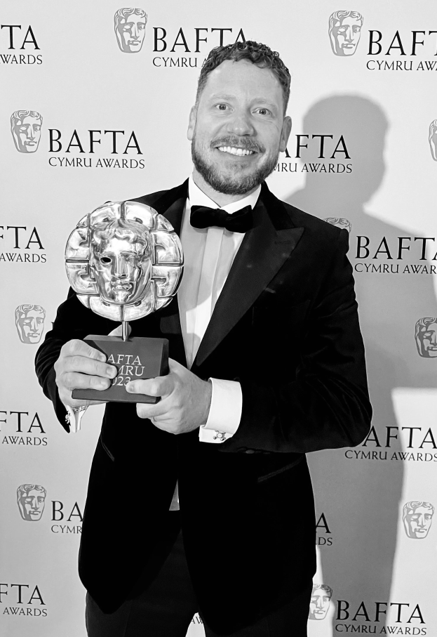 Ein Mann in einem Smoking, der eine BAFTA-Trophäe hält, vor einer Tafel mit der Aufschrift "BAFTA Awards 2018."