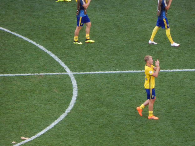 Gruppe von Männern in Fußballtrikots klatscht feiernd auf einem Fußballfeld.
