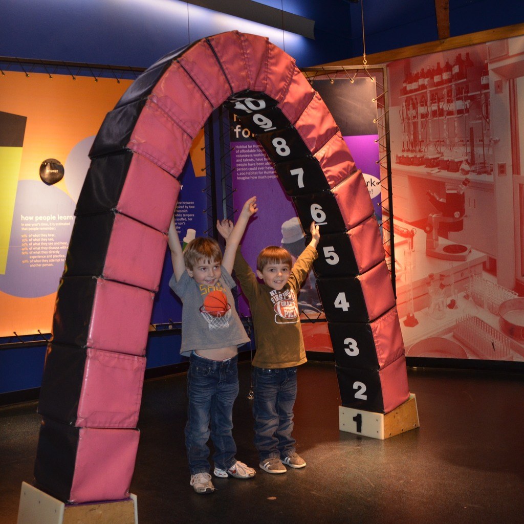 Kinder auf einer kleinen Vergnügungsanlage mit Skateboards am Bildrand.