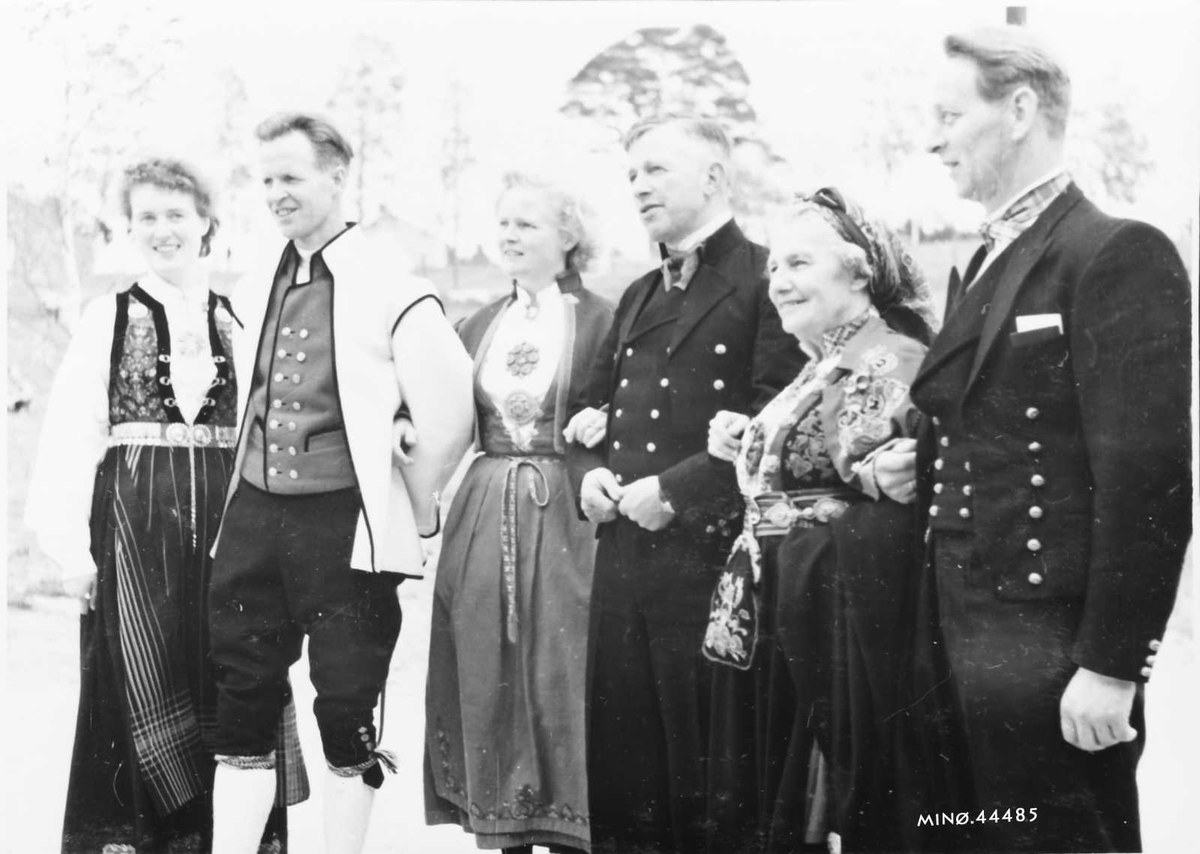 Schwarzes und weißes Foto einer Gruppe von Menschen, die gemeinsam im Freien posieren, mit Bäumen im Hintergrund und Text unten, der 'Bayerische Familie in den 1930er Jahren' lautet.
