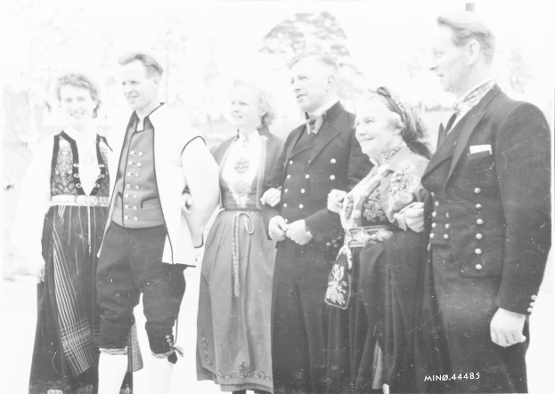 Schwarzes und weißes Foto einer Gruppe von Menschen, die gemeinsam im Freien posieren, mit Bäumen im Hintergrund und Text unten, der 'Bayerische Familie in den 1930er Jahren' lautet.