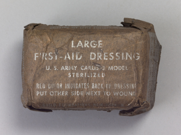 Großer rechteckiger Verbandskasten mit einem großen schwarzen Etikett, auf dem "Großer Verbandskasten" steht, Deckel leicht geöffnet und Inhalt sichtbar.