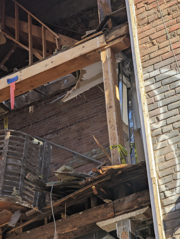 Teilweise abgerissenes Gebäude mit verstreuten Holzplanken und Trümmern, zerbrochene Fenster und Türen nach einer Abriss.