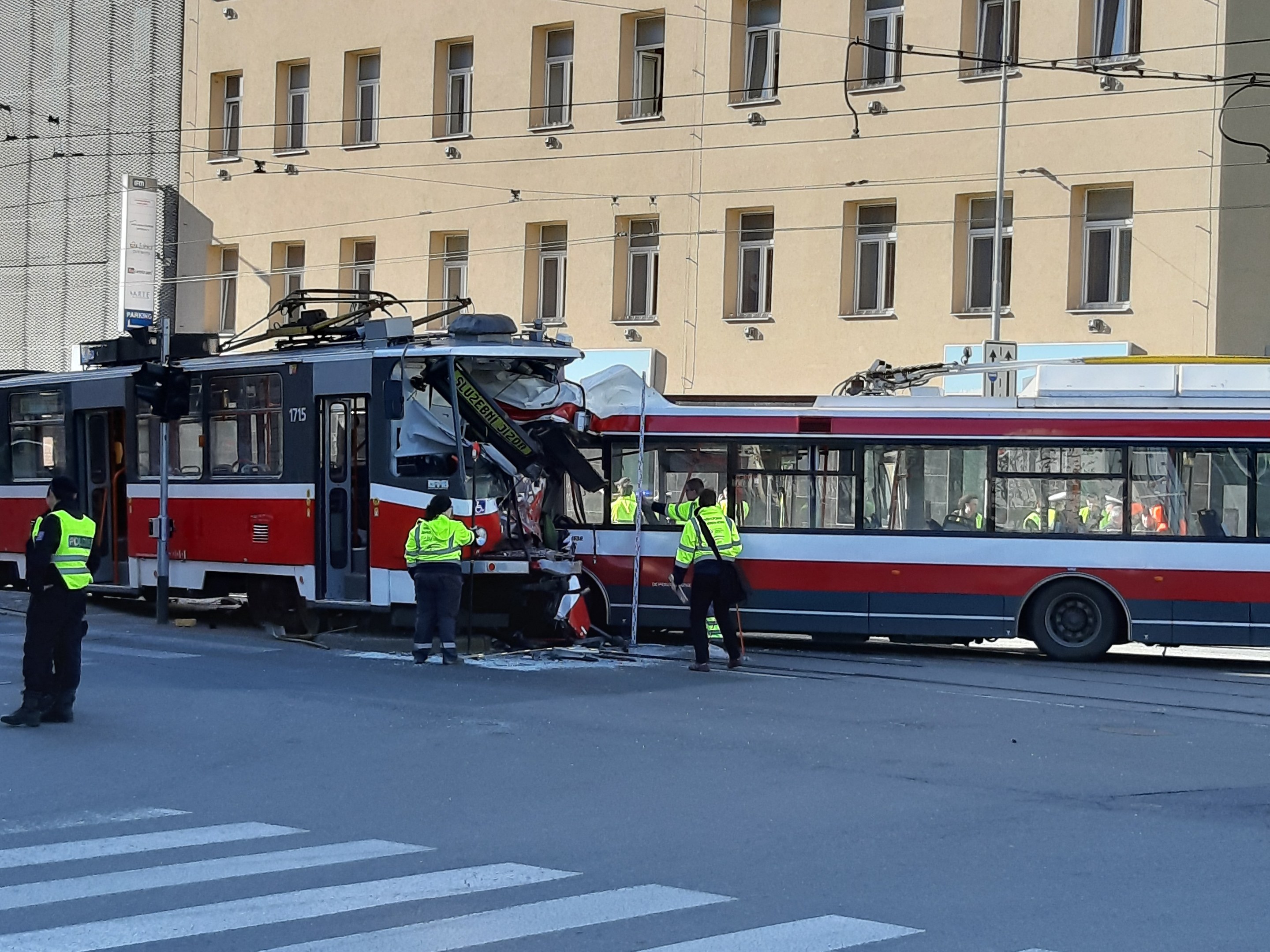 Rote und weiße Tram war in einen Straßenunfall mit wenigen Menschen in der Nähe und einem Gebäude im Hintergrund verwickelt.