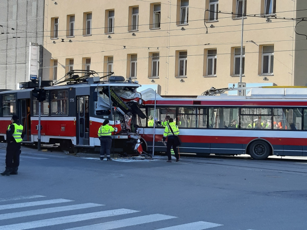 Rote und weiße Tram war in einen Straßenunfall mit wenigen Menschen in der Nähe und einem Gebäude im Hintergrund verwickelt.