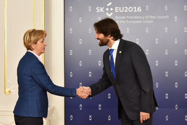 Bundeskanzlerin Angela Merkel und Bundeskanzler Joachim Gauck schütteln sich die Hände und lächeln vor einer Wand mit einem "EU-Gipfel"-Plakat und einer Tür.