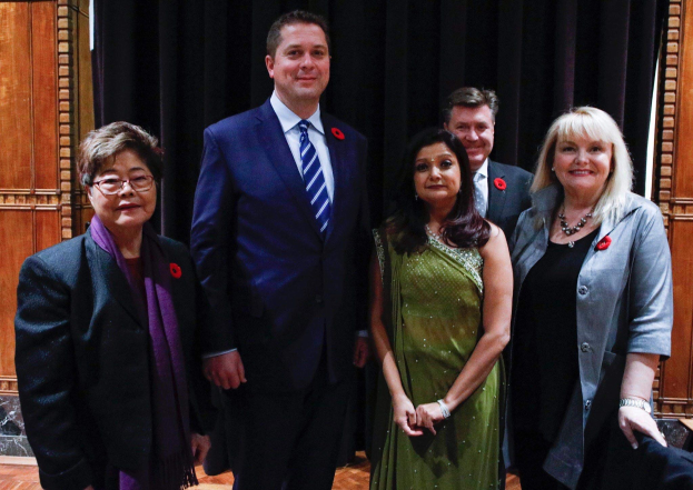 Gruppe von Menschen vor schwarzem Vorhang mit Holzwand im Hintergrund, die scheinbar Mitglieder der FDP bei einer Versammlung sind.