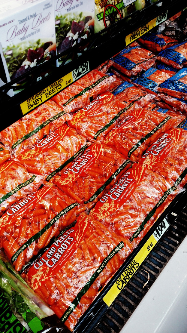 Geschäftsstelle eines Supermarkts mit verschiedenen Lebensmittelpackungen, darunter Gemüse, jeweils mit angehängten Preisschildern.
