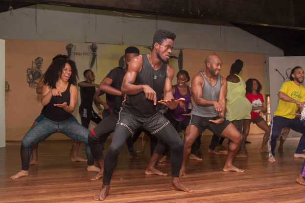 Eine Gruppe von Menschen tanzt in einem Choreografie-Kurs an der Universität Chicago, mit einer Wand, die mit Gemälden geschmückt ist.
