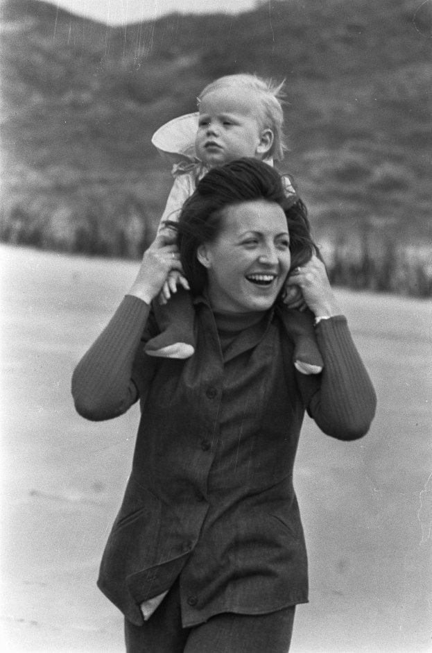 Eine Frau, die lächelt, während sie ein Baby hält, mit einem sanft unscharfen Hintergrund, der einen nostalgischen Effekt erzeugt.