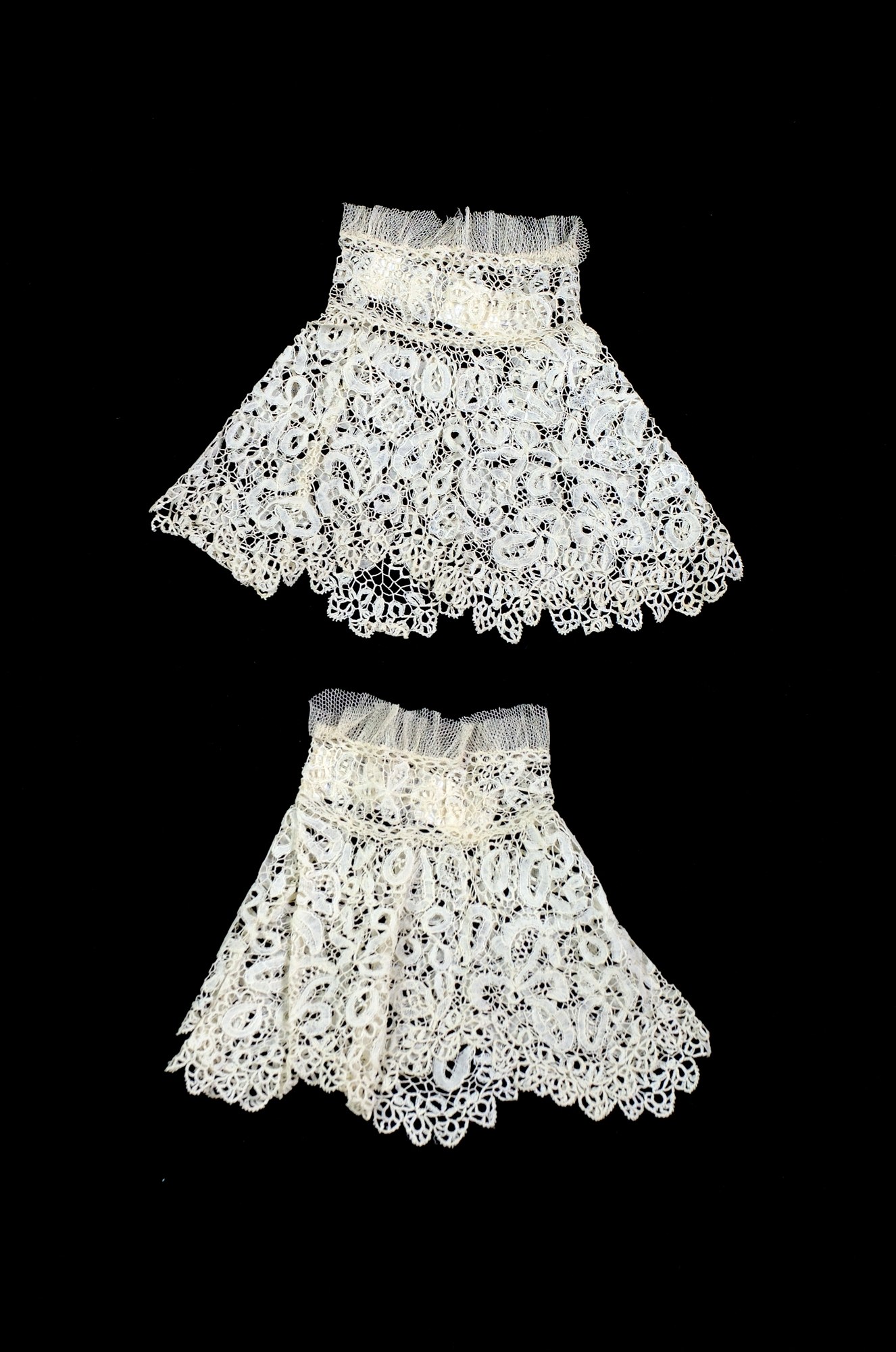 Zwei weiße Spitze-Röcke mit zarten Mustern auf schwarzem Hintergrund.