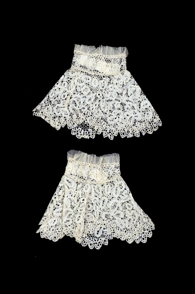 Zwei weiße Spitze-Röcke mit zarten Mustern auf schwarzem Hintergrund.
