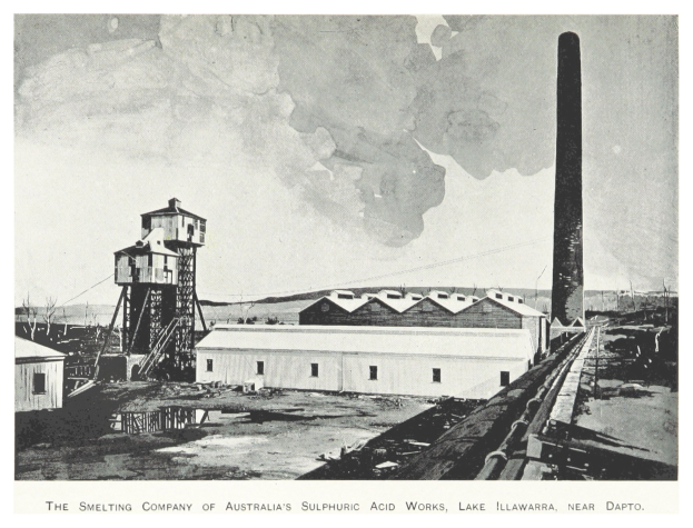 Schwarzes und weißes Foto einer Industrieanlage mit mehreren Gebäuden, einem hohen Turm und Rauch, der aus einem Schornstein aufsteigt, mit Text unten.