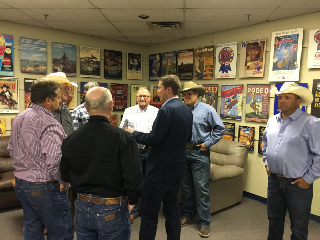 Eine Gruppe von Männern in einem Raum mit Sofas, Postern an den Wänden und Deckenlampen, die sich unterhalten.