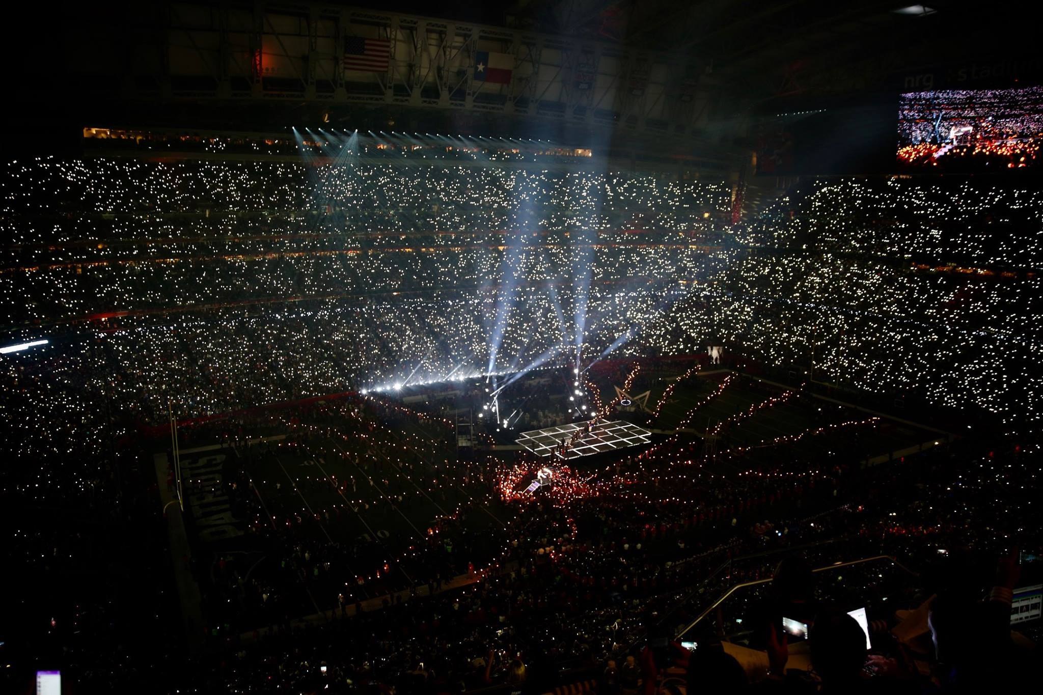 Gro├čes Publikum in einem hell erleuchteten Stadion bei Nacht mit einem Bildschirm, der die Ergebnisse der Super Bowl XLVII-Halbzeit auf der rechten Seite anzeigt.
