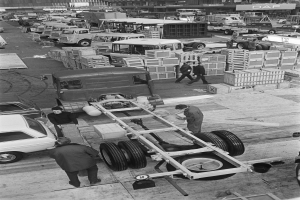 Schwarze und weiße Fotografie von Männern, die an einem Truck in einer Fabrik arbeiten.